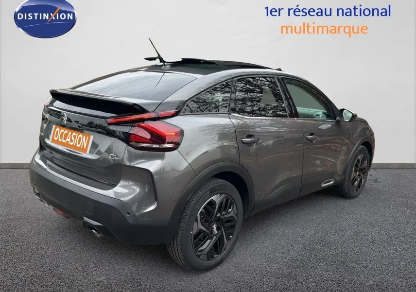 Vue 3/4 arrière droite d'une Citroën C4 gris métallisé avec jantes noires et toit panoramique ouvrant.