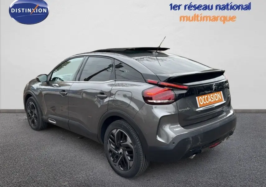 Vue 3/4 arrière droite d'une Citroën C4 gris métallisé avec toit noir et jantes noires biton.