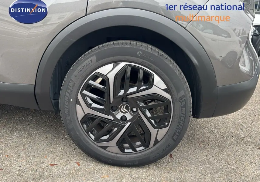 Gros plan sur la roue arrière droite d'une Citroën C4 gris 2021 avec jante alliage bicolore et pneus Michelin.