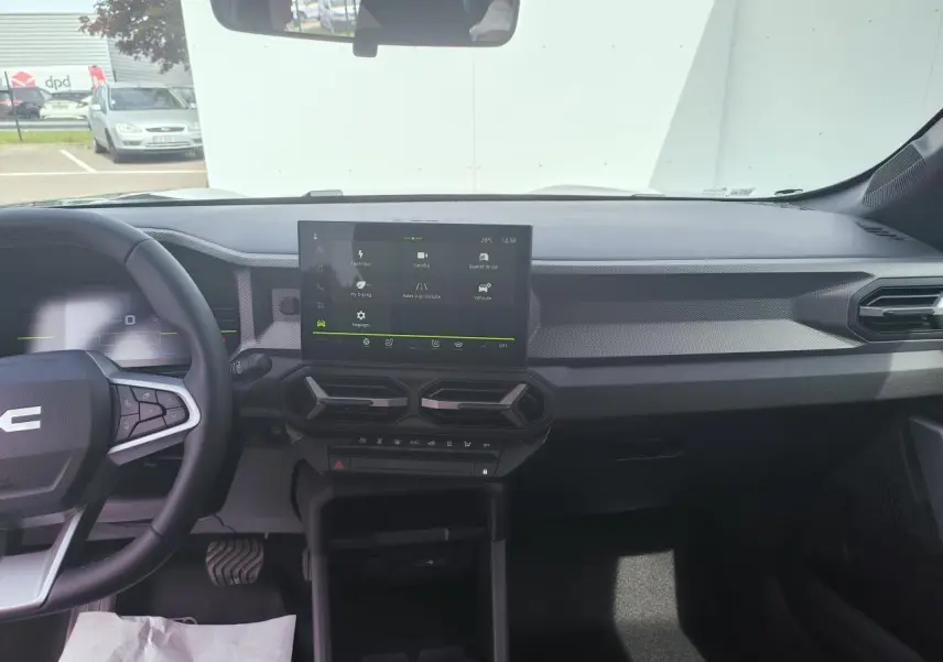 Vue intérieure avant du tableau de bord du Dacia Duster III gris schiste, avec écran tactile central et volant multifonction.