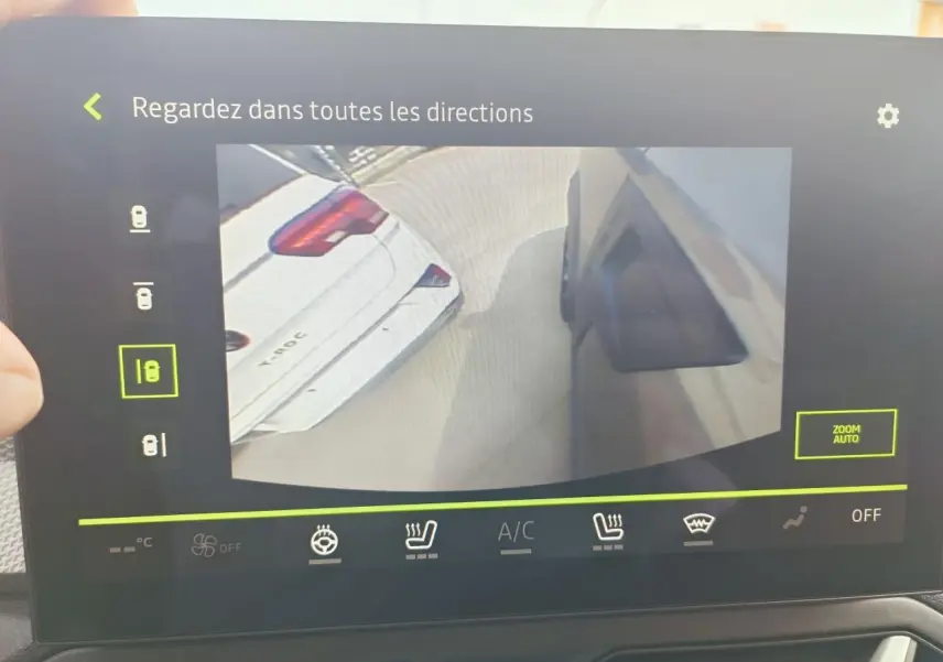 Écran tactile intérieur montrant la caméra multivues du Dacia Duster III gris schiste, vue latérale et arrière du véhicule.