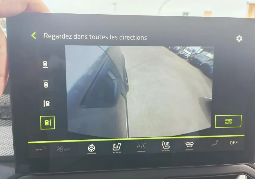 Vue caméra latérale gauche du Dacia Duster gris schiste métal, montrant le côté du véhicule et le sol adjacent.