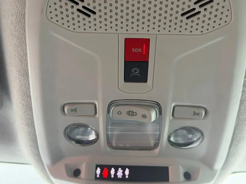 Vue en gros plan du panneau de commandes de plafond intérieur du Citroën C4 X 2024, avec bouton SOS rouge et éclairage intégré.
