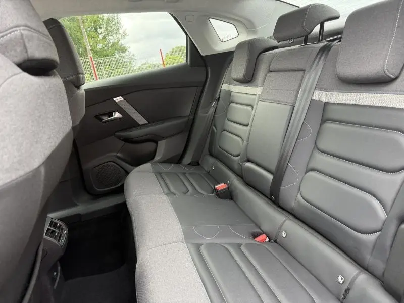 Vue intérieure arrière côté droit du Citroën C4 X 2024, sièges en tissu et cuir gris avec ceinture de sécurité visible.