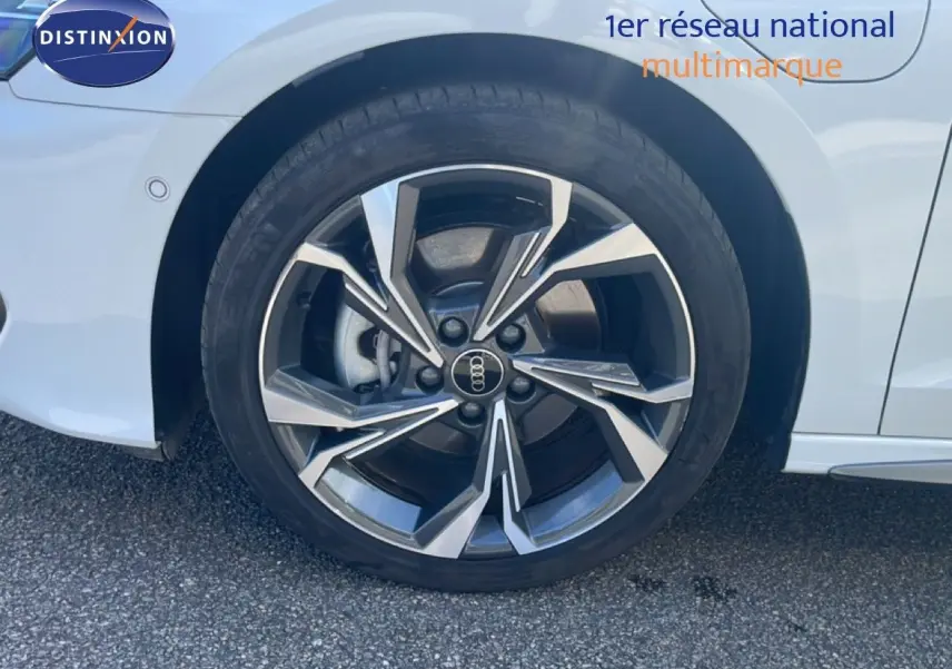 Gros plan sur la roue avant droite d'une Audi A3 Sportback blanche avec jante alliage au design moderne.