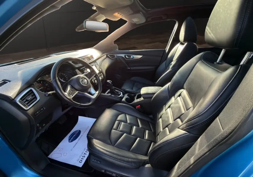 Vue intérieure côté conducteur du Nissan Qashqai bleu 2018, sièges cuir noirs et tableau de bord moderne.