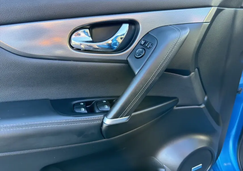 Détail de la porte avant gauche du Nissan Qashqai bleu 2018, avec poignée chrome et commandes électriques.