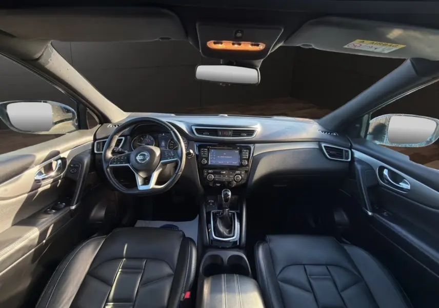 Vue intérieure avant du Nissan Qashqai Tekna+ 2018, montrant le tableau de bord noir et le volant cuir multifonctions.