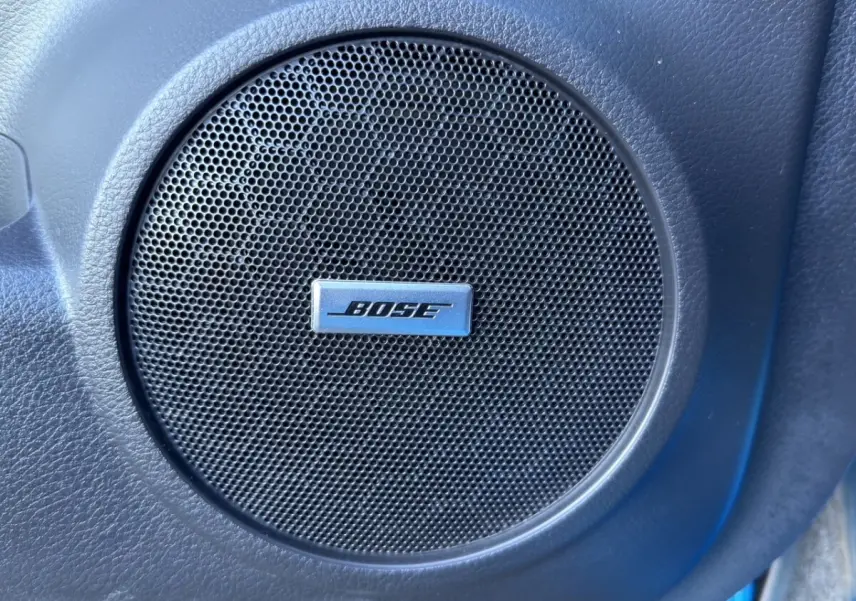 Gros plan sur le haut-parleur Bose intégré dans la porte intérieure d’un Nissan Qashqai bleu 2018.