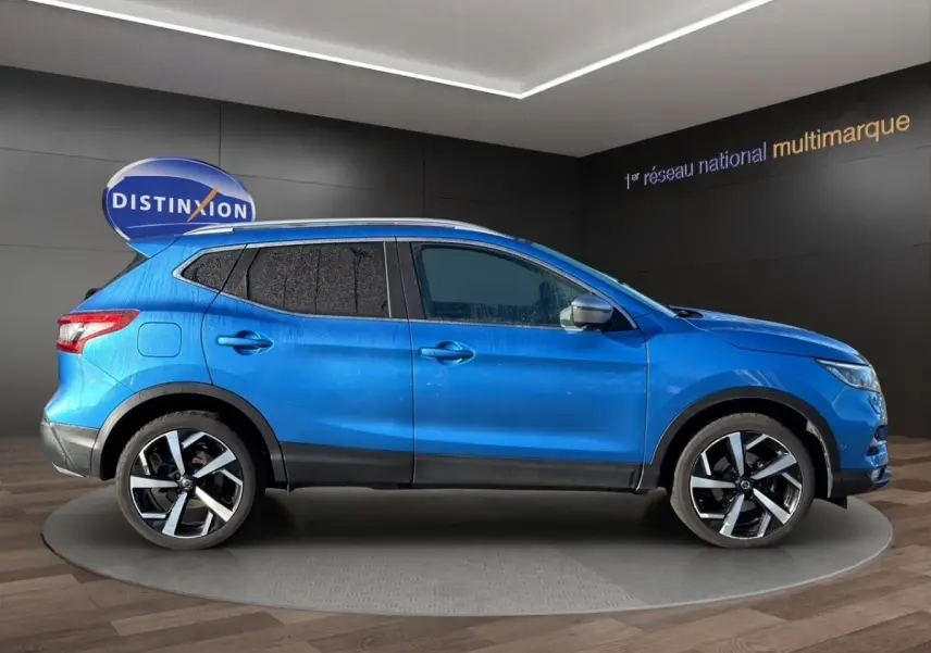 Vue latérale droite d'un Nissan Qashqai bleu 2018 avec jantes alliage et vitres teintées en showroom.