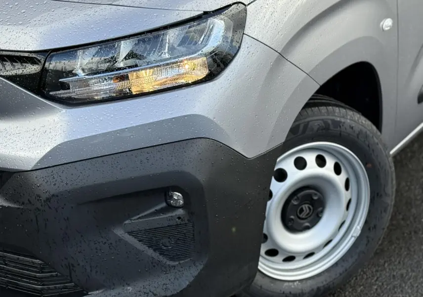 Gros plan sur l'avant droit gris Artense du Citroën Berlingo 2025 avec phare allumé et jante tôle 16 pouces.