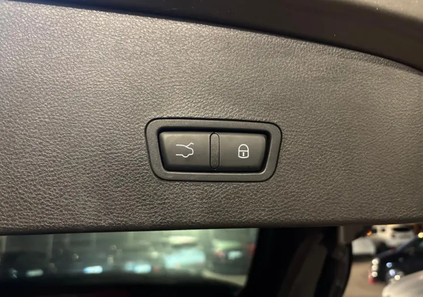 Gros plan sur les boutons de fermeture et verrouillage électrique du hayon intérieur d'un Alfa Romeo Tonale gris.