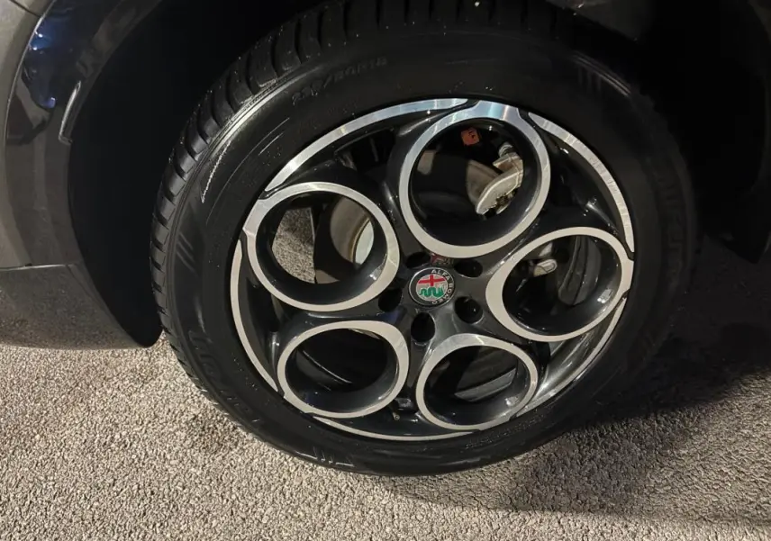 Gros plan sur la jante alliage 18 pouces noire et argentée de l'Alfa Romeo Tonale gris, avec logo central visible.