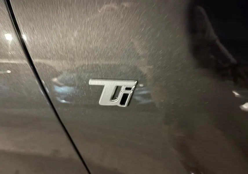 Gros plan sur l'emblème Ti sur la porte gris métallisé de l'Alfa Romeo Tonale 2023 hybride rechargeable.