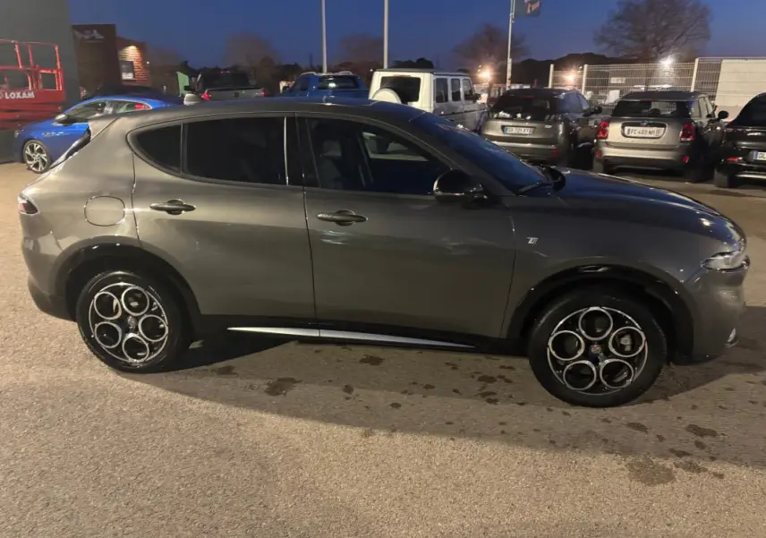 Vue de profil côté gauche d'une Alfa Romeo Tonale gris métallisé 2023 avec jantes alliage distinctives en cercle.