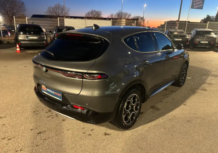 Vue 3/4 arrière droite d'une Alfa Romeo Tonale gris métallisé avec jantes alliage 18 pouces au crépuscule.