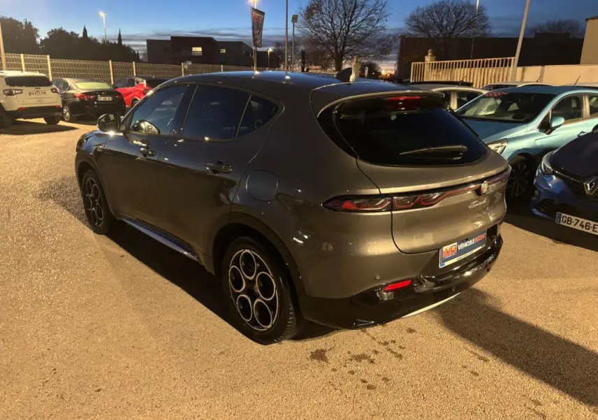 Vue 3/4 arrière droite d'une Alfa Romeo Tonale gris métallisé avec jantes alliage 18 pouces, stationnée en extérieur au crépuscule.