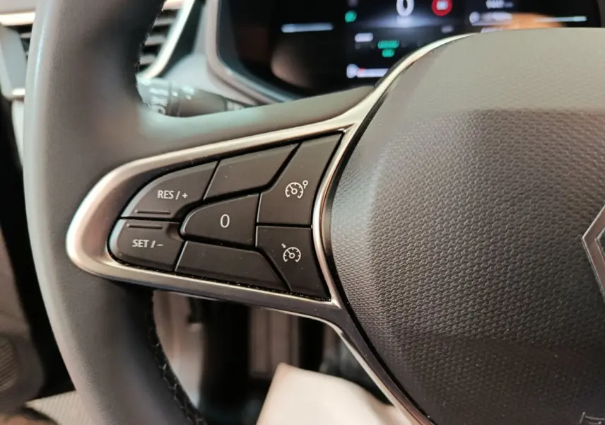 Gros plan sur les commandes du régulateur de vitesse au volant cuir de la Renault Clio Evolution Blue dCi 100 noir.