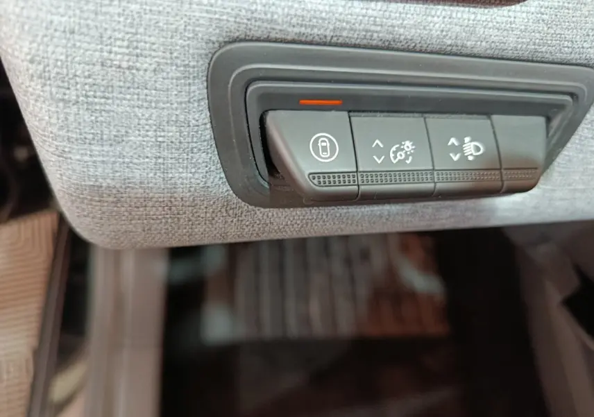 Détail des commandes d’éclairage et verrouillage sur tableau de bord tissu clair de Renault Clio noir 2025.