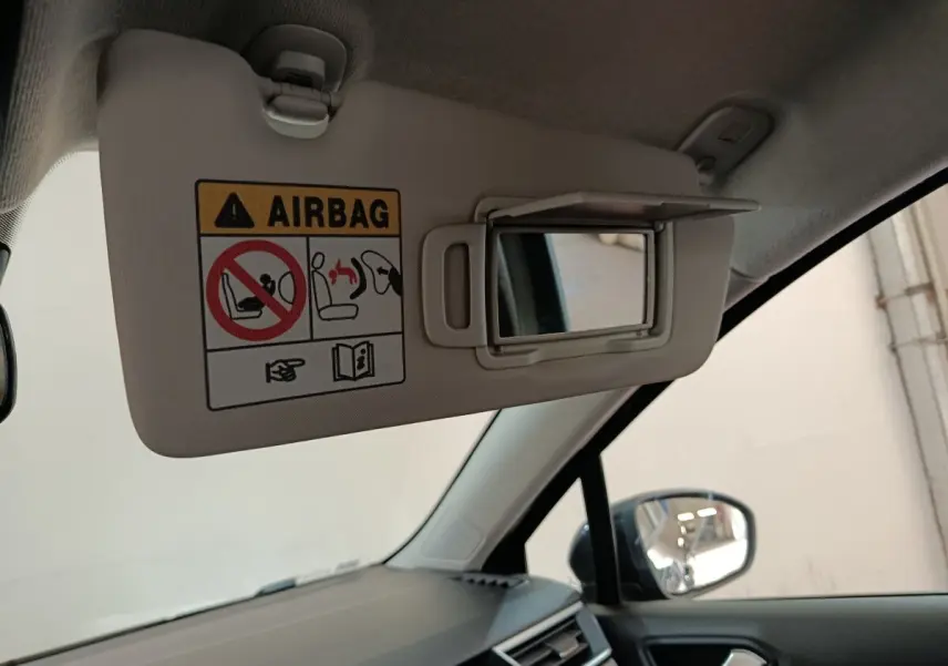 Détail intérieur montrant le pare-soleil côté conducteur avec miroir et avertissement airbag dans une Renault Clio noire.