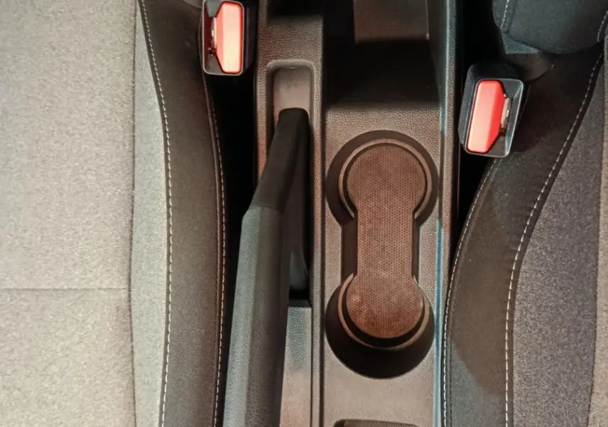 Vue plongeante sur la console centrale noire de la Renault Clio 2025, avec frein à main et porte-gobelets entre sièges gris.