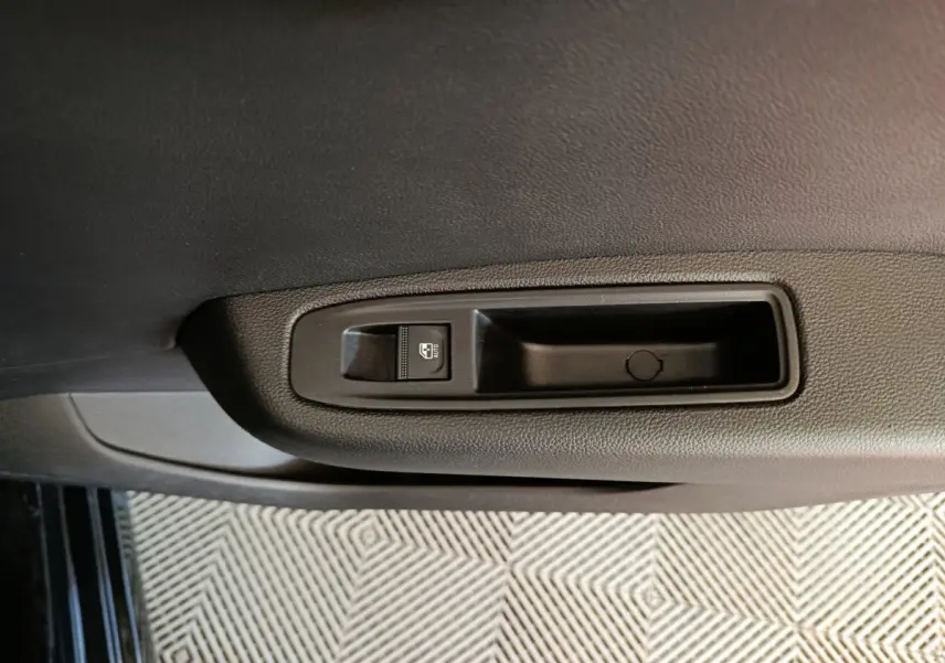 Gros plan sur la commande de lève-vitre côté conducteur de la Renault Clio noire Evolution Blue dCi 100 -25, intérieur.