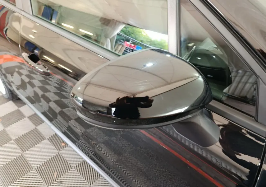 Rétroviseur côté conducteur noir brillant de la Renault Clio Evolution Blue dCi 100, vue rapprochée sur la portière avant.