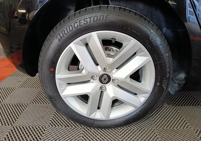 Gros plan sur la roue avant droite noire d'une Renault Clio 2025 avec jante argentée et pneu Bridgestone.