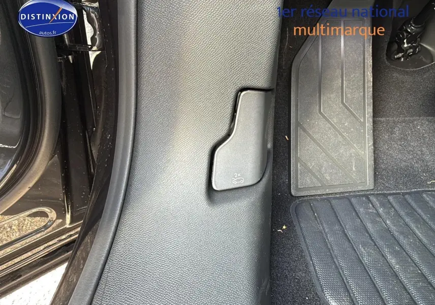 Détail intérieur côté gauche au niveau du plancher avec commande d'ouverture du coffre sur Peugeot 3008 gris titane 2024.