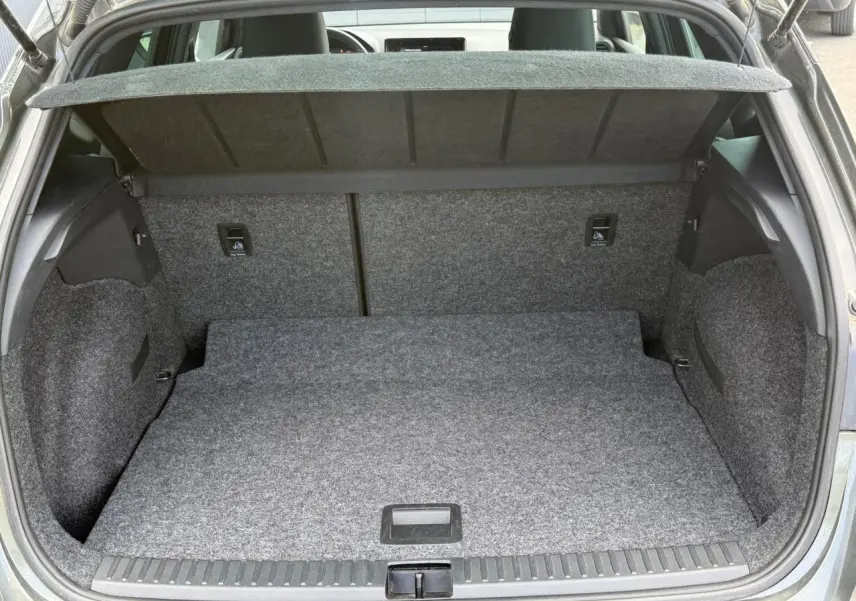 Coffre ouvert vu de l'arrière d'un SEAT Arona Gris Cliff, montrant un plancher plat et une moquette grise uniforme.