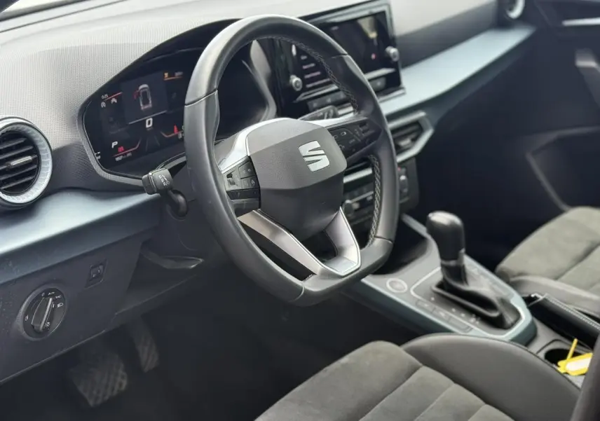 Vue intérieure côté conducteur du tableau de bord et volant noir du SEAT Arona 2025 avec sellerie suédine.