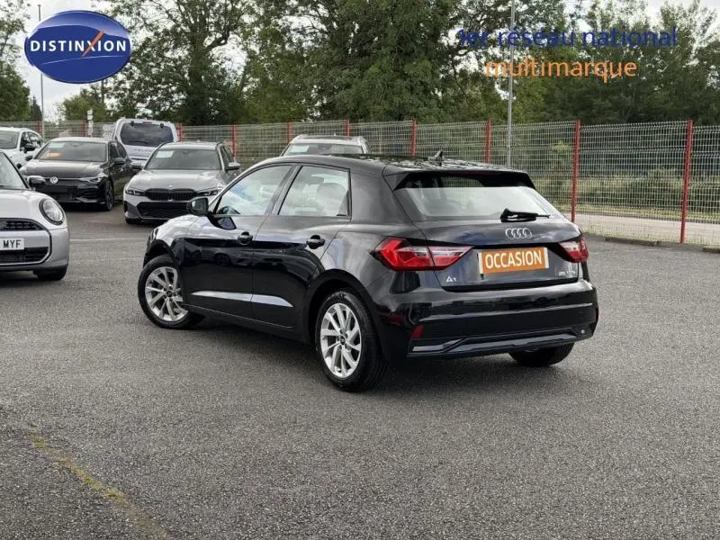 Audi A1 Sportback 2023 noir Mythic métallisé, vue 3/4 arrière côté gauche sur parking multimarque.
