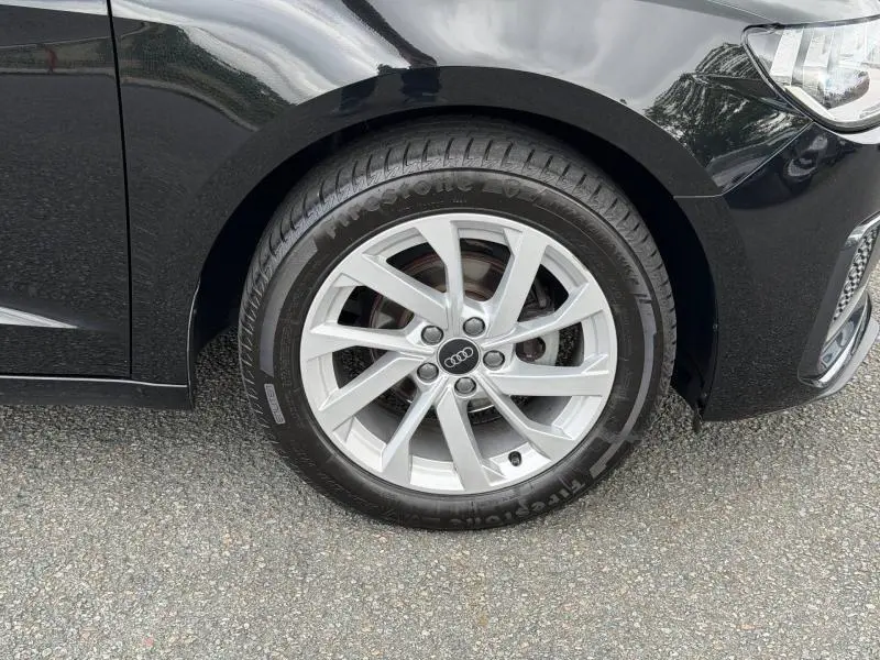 Gros plan sur la roue avant gauche de l'Audi A1 Sportback 25 TFSI 2023 en Noir Mythic métallisé avec jante argentée.