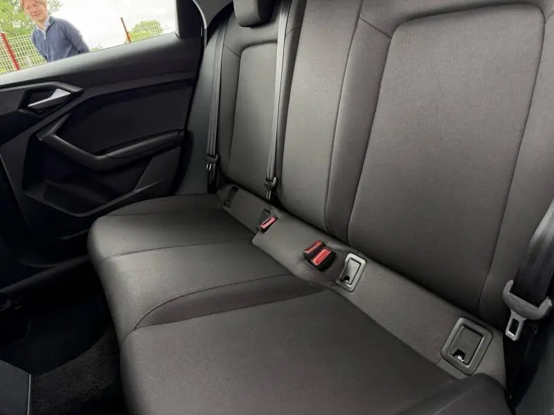 Vue intérieure du siège arrière droit de l'Audi A1 Sportback 2023 en tissu noir, avec ceintures de sécurité visibles.