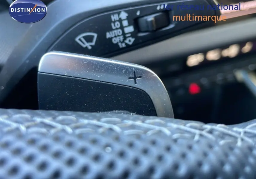 Gros plan sur la palette de changement de vitesse "+" en aluminium brossé dans l'habitacle d'une Audi A3 Sportback noire.