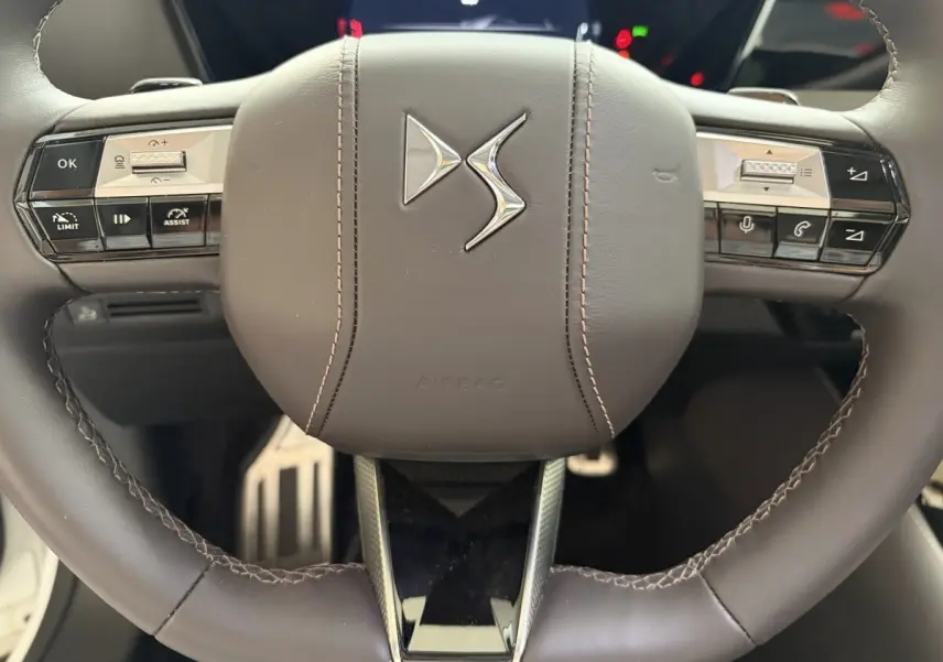 Gros plan sur le volant cuir marron du DS4 2024 avec commandes multifonctions et logo DS central.