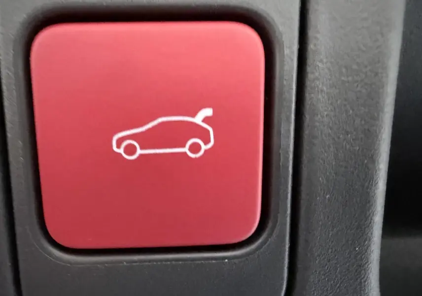 Bouton rouge intérieur du DS4 2024 avec pictogramme de coffre ouvert, vue en gros plan.
