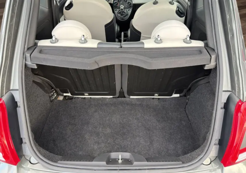 Coffre ouvert vu de l'arrière d'une FIAT 500 gris foncé avec banquette arrière beige et tablette de coffre.