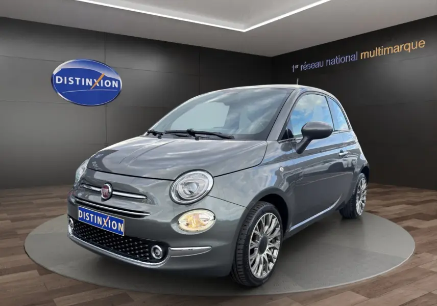 Fiat 500 gris foncé vue 3/4 avant droit, avec phares ronds et jantes alliage multibranches visibles.