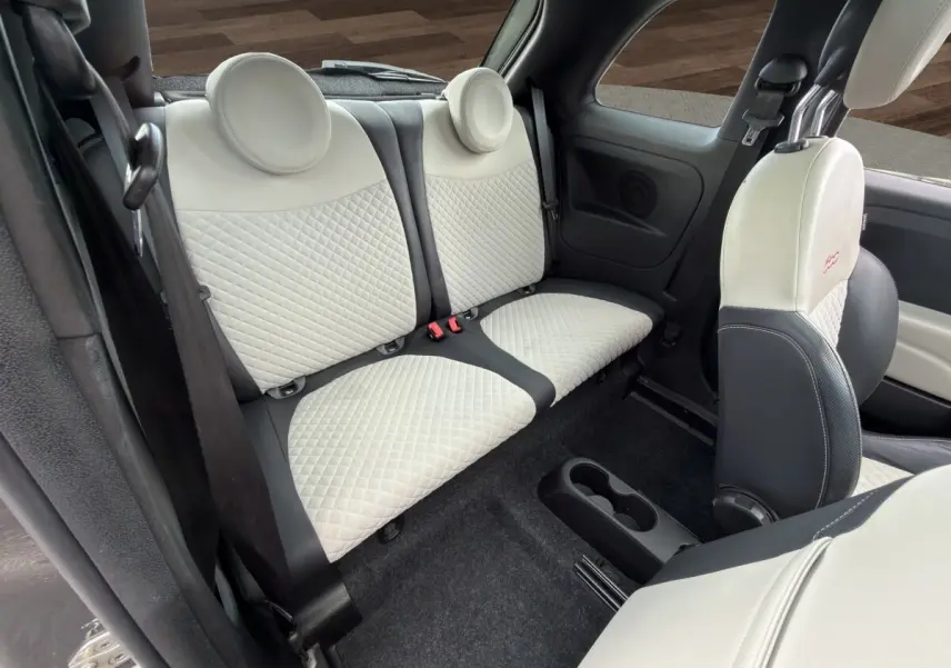 Vue intérieure arrière de la Fiat 500 1.0 gris foncé, sièges arrière et avant en cuir clair matelassé avec logo brodé.