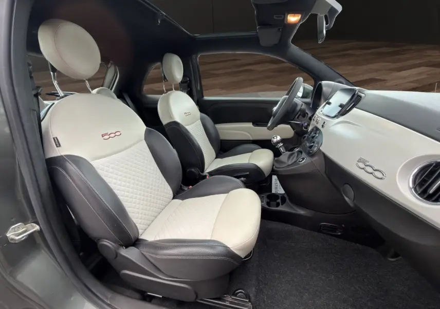 Intérieur de la Fiat 500 2020 vu côté gauche, sièges bicolores crème et noir avec logo 500 brodé.