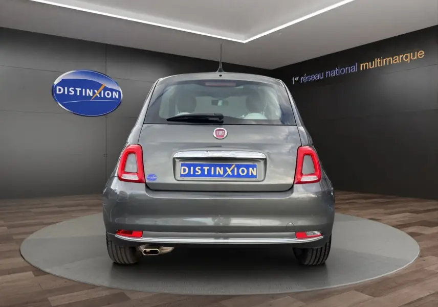 Vue arrière d'une FIAT 500 gris foncé avec feux arrière distinctifs et échappement visible en showroom.