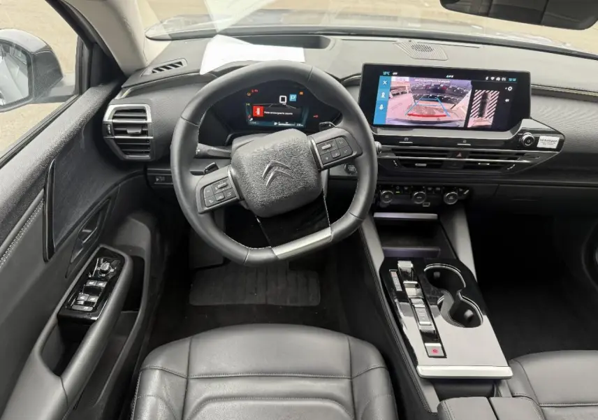 Vue intérieure centrée sur le poste de conduite du Citroën C5 X 2024, avec écran tactile et volant multifonction noir.