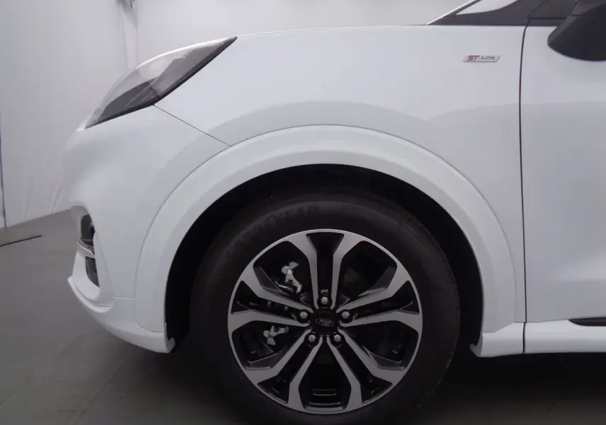 Gros plan sur la roue avant droite et l'aile blanche d'un Ford Puma 1.0 EcoBoost MHEV 2022 finition ST-Line.