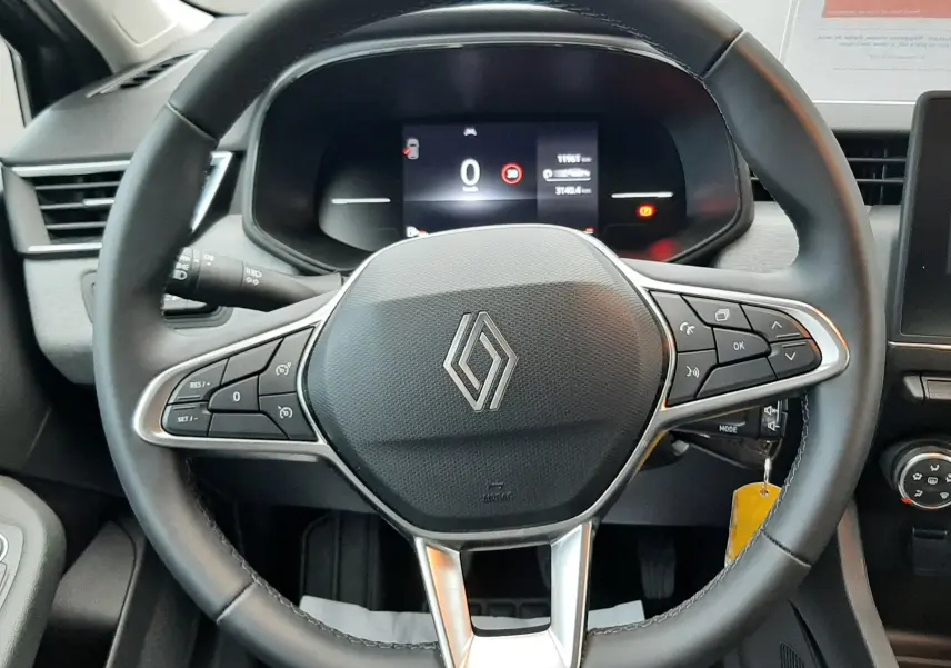 Volant noir de Renault Clio V TCE 90ch Evolution 2025 vu de face avec commandes intégrées et tableau de bord numérique.