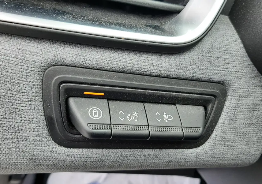 Gros plan sur les commandes de réglage d'éclairage et verrouillage sur tableau de bord gris tissu d'une Renault Clio V gris schiste.