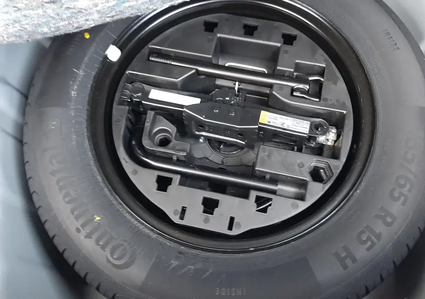 Gros plan sur la roue de secours et le kit d'outils intégrés dans le coffre d'une Renault Clio V gris schiste 2025.