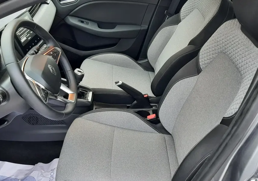 Vue intérieure côté conducteur de la Renault Clio V TCE 90ch Evolution 2025 avec sièges tissu gris et volant multifonction.