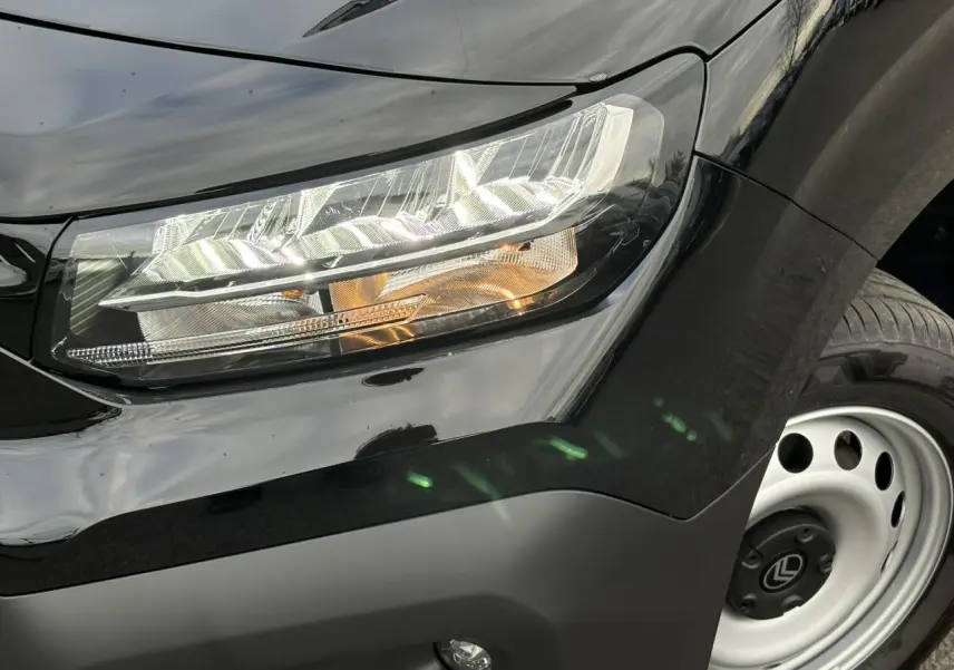 Gros plan sur le phare avant droit et la roue acier du Citroën Berlingo Van XL noir Perla 2025.