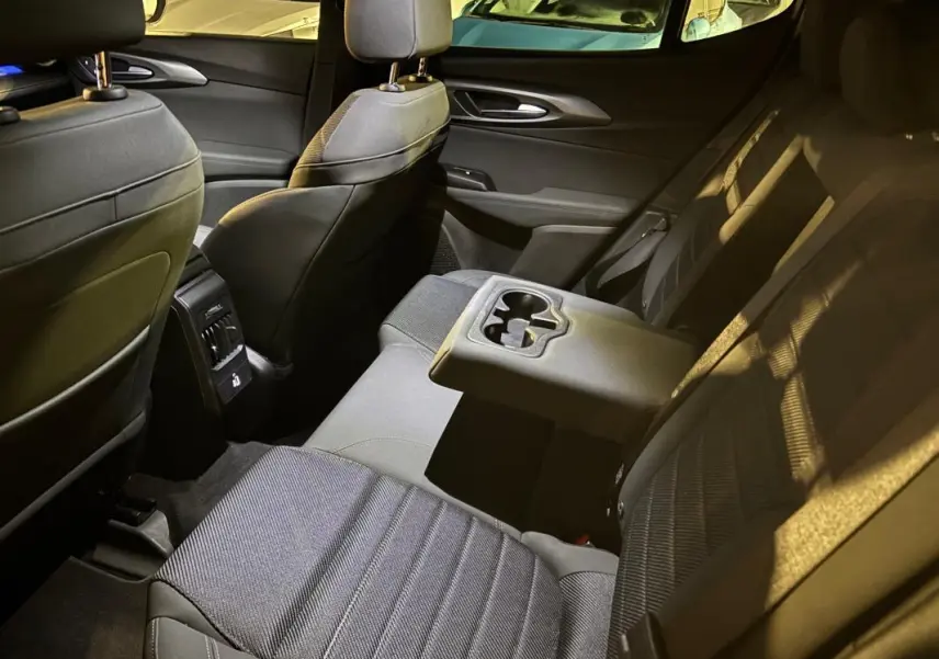 Vue intérieure arrière côté droit de l'Alfa Romeo Tonale 1.3 hybride, sièges noirs avec accoudoir central et porte-gobelets.